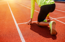 A runner is in the starting position, getting ready for a sprint race on a track at sunrise, full of determination