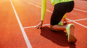 A runner is in the starting position, getting ready for a sprint race on a track at sunrise, full of determination